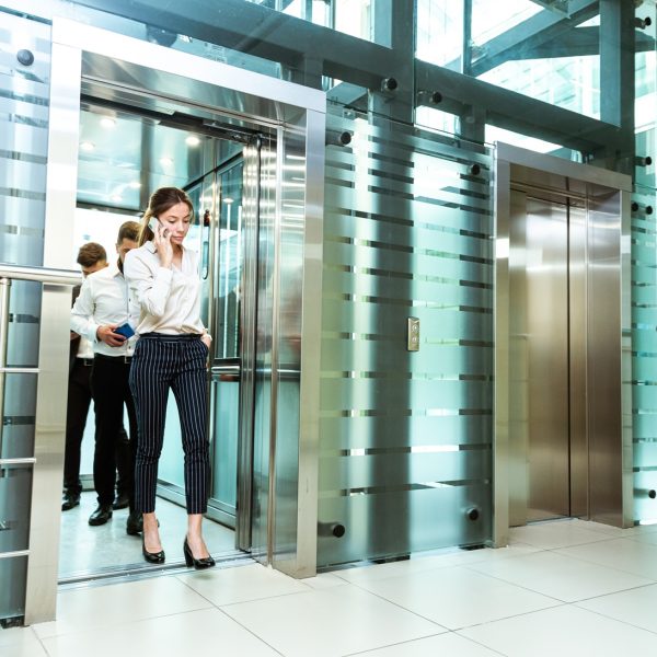 Business team group going on elevator. Business people in a large glass elevator in a modern office. Corporate businessteam and manager in a meeting
